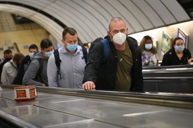 Dojeżdżający do pracy noszą maski na twarzach, gdy przechodzą przez stację metra Vauxhall