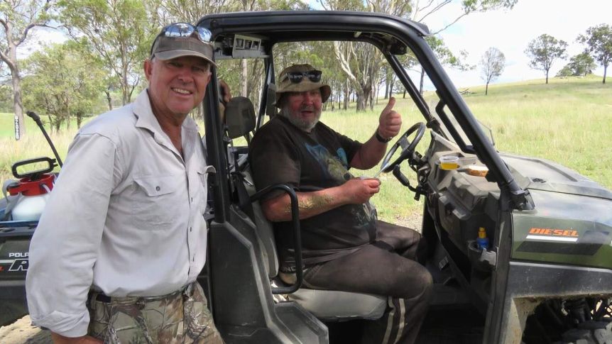 Two men smiling, one of them sitting in a utility terrain vehicle